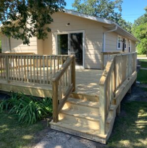 Natural wood deck with 4 steps and railing surrounding