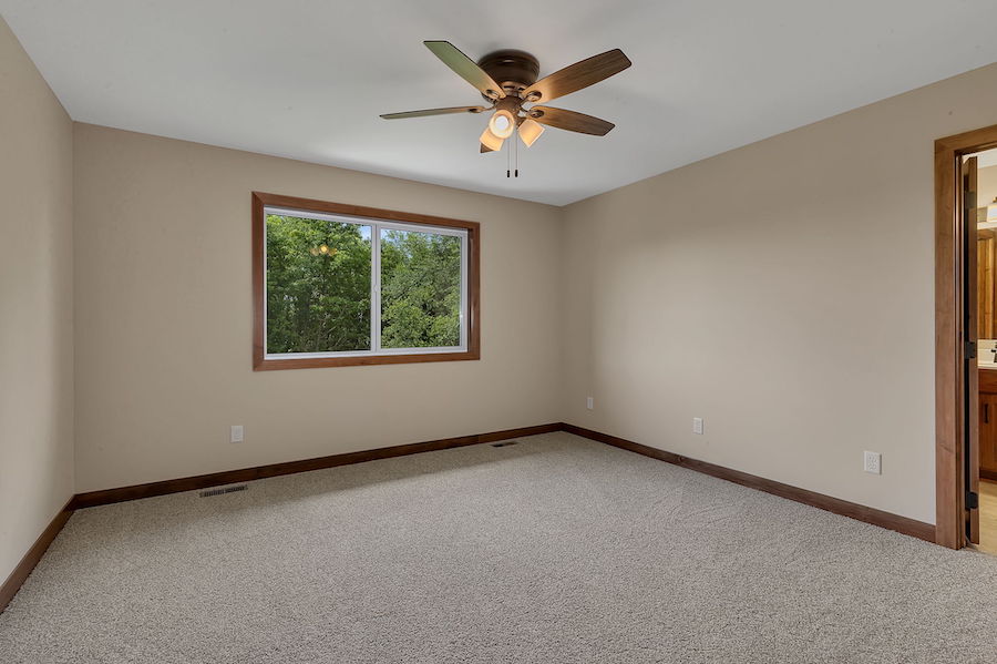 Carpeted large bedroom with ceiling fan light