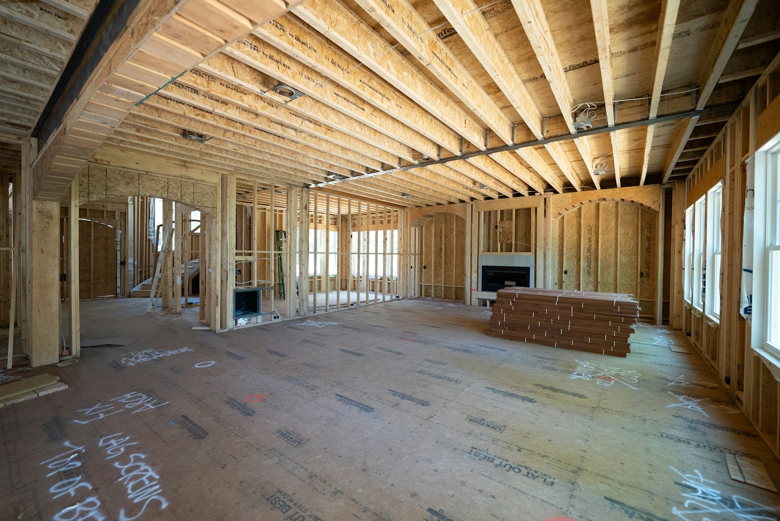 A large room with exposed wooden wall studs and subflooring during a major renovation.