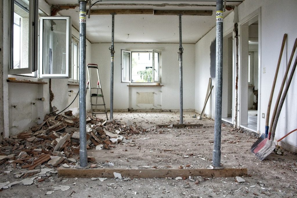 A room undergoing major structural renovation with metal support poles and construction debris.