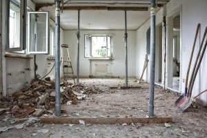 A room undergoing major structural renovation with metal support poles and construction debris.